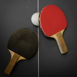 Top view of two ping pong paddles and ball on a table tennis setup.
