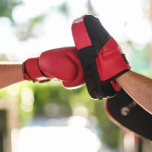 Close-up of training in boxing using gloves and focus mitts outdoors.