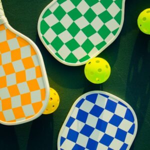 Vibrant pickleball paddles and balls arranged on a sunny sports court.