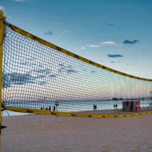 A beach volleyball net on a sandy shore at Gdańsk with a serene sunset sky.