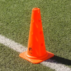 A vibrant orange traffic cone placed on a synthetic grass sports field.