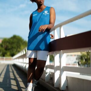 Woman wearing sports outfit leaning on a bridge in Berlin with vibrant blue sky.