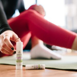 Focused shot of a woman applying CBD balm during a yoga session indoors.