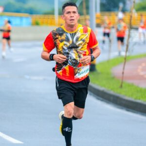 Adult male runner in a colorful shirt participating in a city marathon. Strong focus and determination.