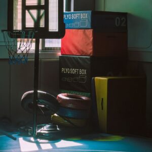 Dimly lit indoor gym with basketball hoop and exercise equipment, creating a moody athletic atmosphere.