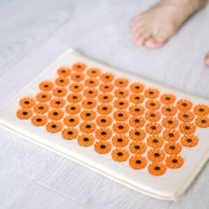 Close-up of a foot acupressure mat on a wooden floor, ideal for relaxation therapies.