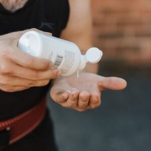 Close-up of a weightlifter applying liquid chalk to hands for grip.