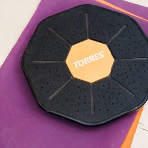 From above of round balance fitness disc placed on folded mats in modern gym