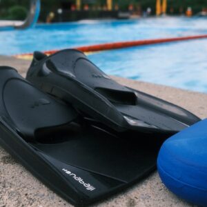 a pair of black flippers sitting next to a swimming pool