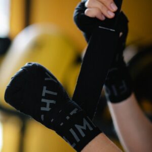 Side view of crop faceless athlete putting on boxing wraps on blurred background