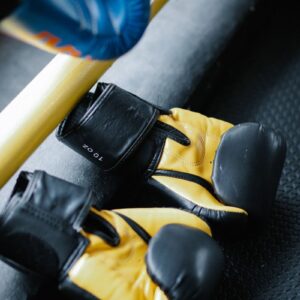 Yellow and black boxing gloves on a gym mat, emphasizing sports training equipment.