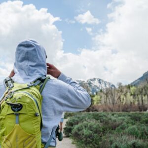 man in white hoodie and green backpack standing on mountain during daytime